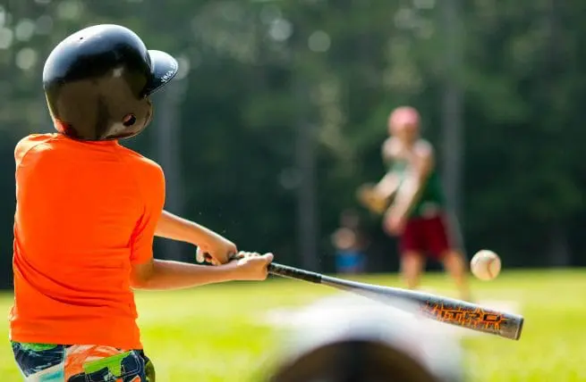 a boy swinging a baseball bat at a ball