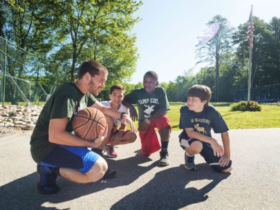 boys and a coach kneeling on a basketball court