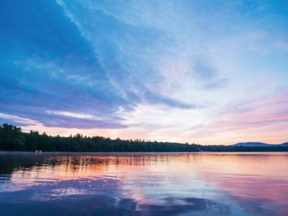 clear calm lake reflecting a beautiful purple sunset