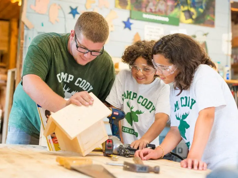 an instructor showing a birdhouse to two campers