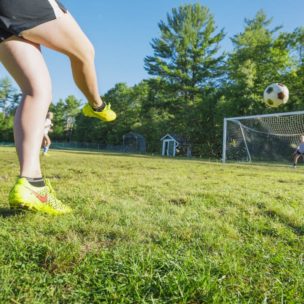 girl kicking a soccer ball into a net