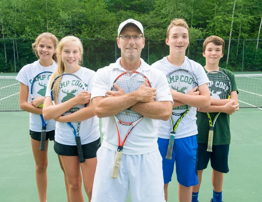 a tennis coach flanked by two people on both sides of him holding tennis rackets