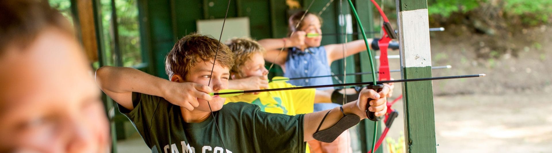 line of boys and girls getting ready to shoot a bow and arrow