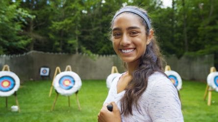 girl smiling in front of archery targets
