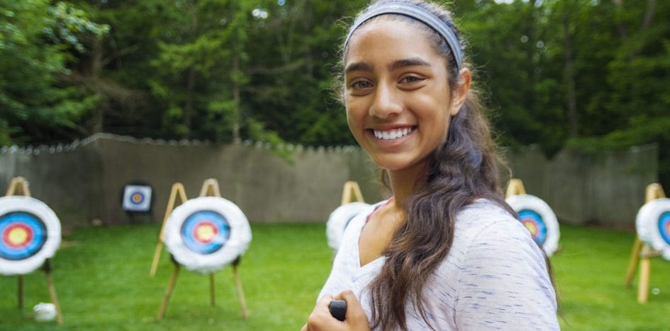 girl smiling in front of archery targets