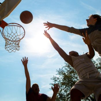boys reaching for a basketball rebound