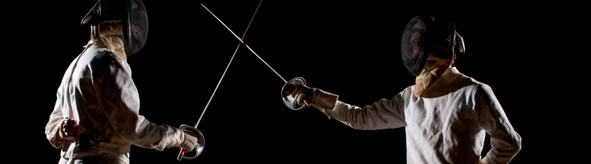 two young boys with fencing masks and jackets and sabres