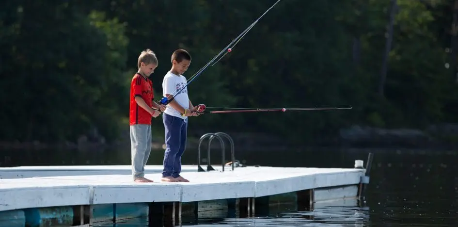 two young boys fishing on a pier