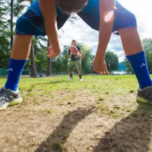 boy hiking a football to an instructor behind him