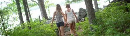 two girls walking down a path in the woods