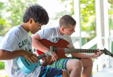 two young boys playing a guitar and ukeleke