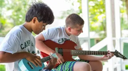 a boy playing the uke while another plays a guitar