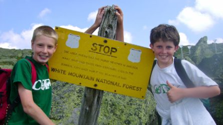 boys smiling next to sign for white mountain national forest