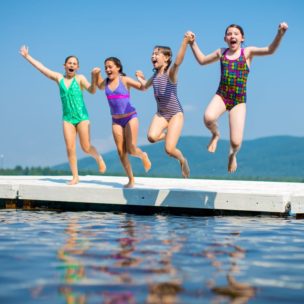 four girls jumping into a lake