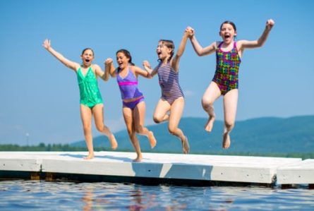 four young girls jumping into a lake