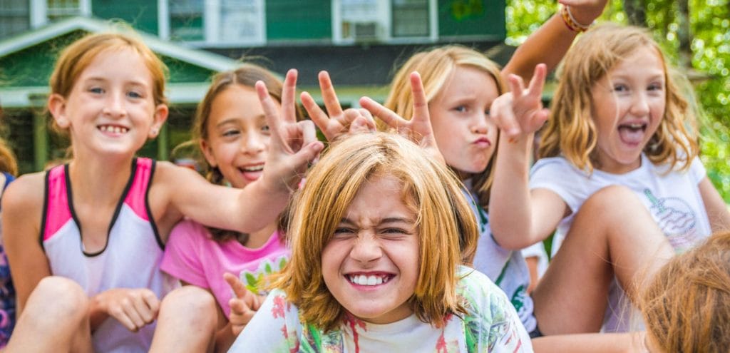 girls at summer camp making bunny ears with hands