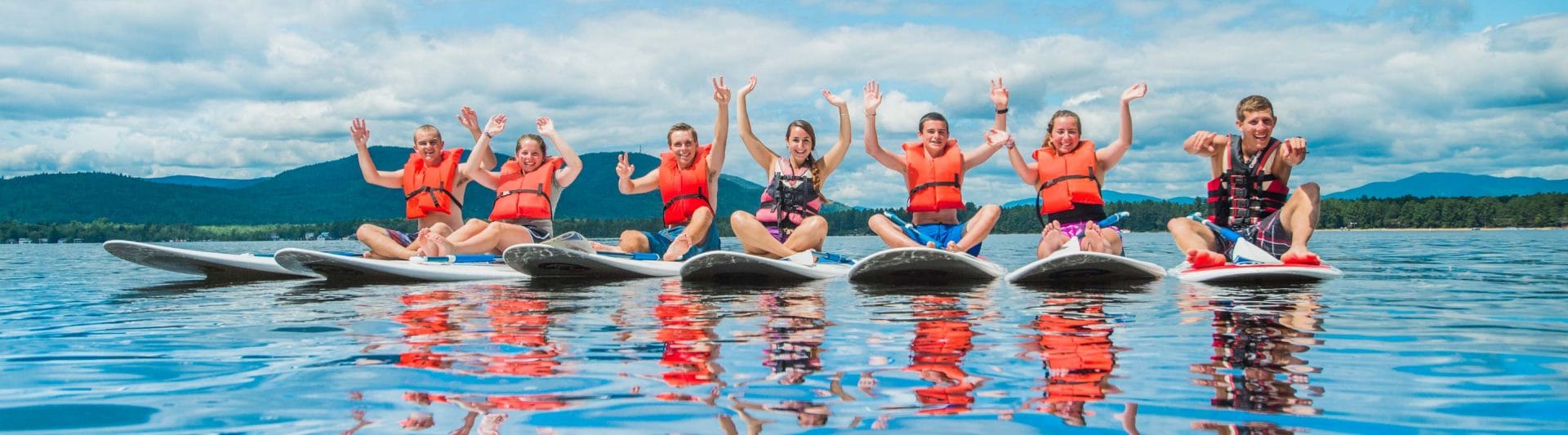 campers sitting on paddle boats waving their hands in the air