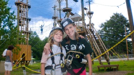 two girls smiling in front of an aerial park