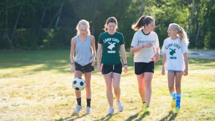 four girls walking with a soccer ball
