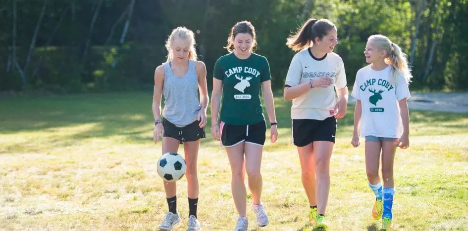 four girls walking with a soccer ball