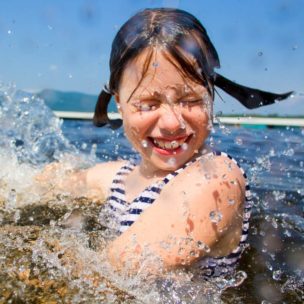 girl smiling and closing her eyes as water is splashing her
