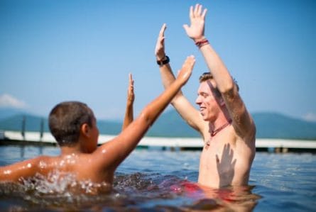 campers high fiving a counselor in the lake