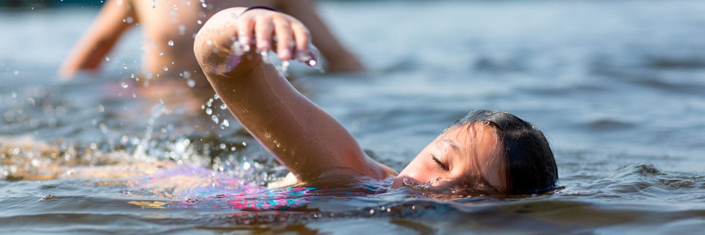 girl swimming in lake at summer camp