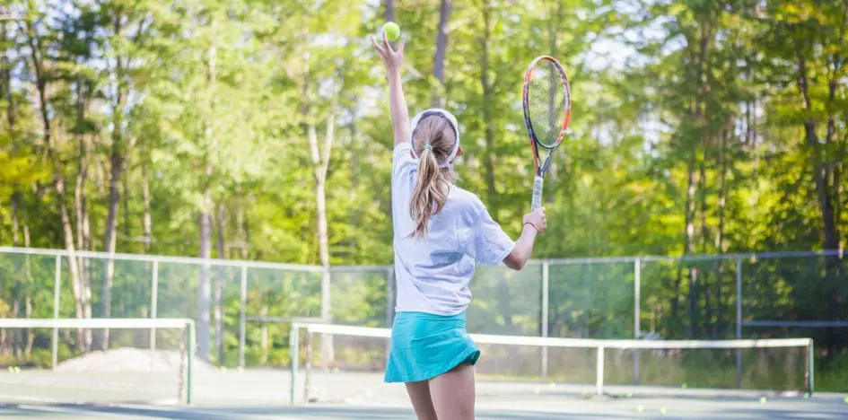 girl tossing a tennis ball to serve