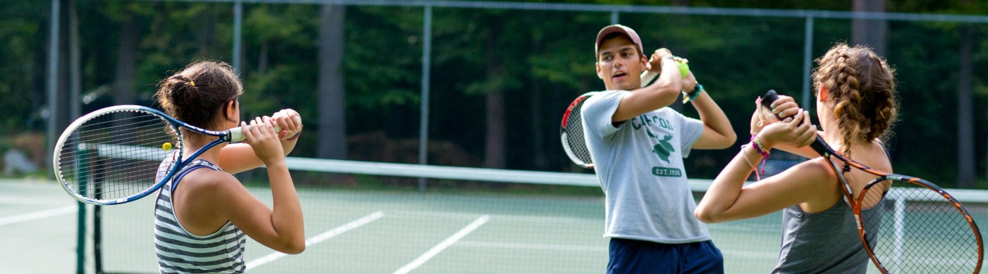 an instructor showing how to do a proper follow through with a tennis forearm swing