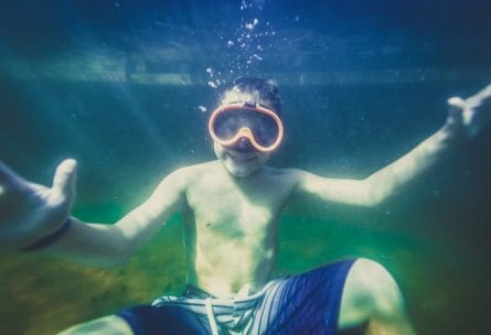 a boy underwater with snorkeling goggles on