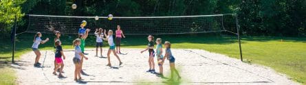 campers playing beach volleyball on a sand court