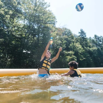 kids hitting volleyball in lake.