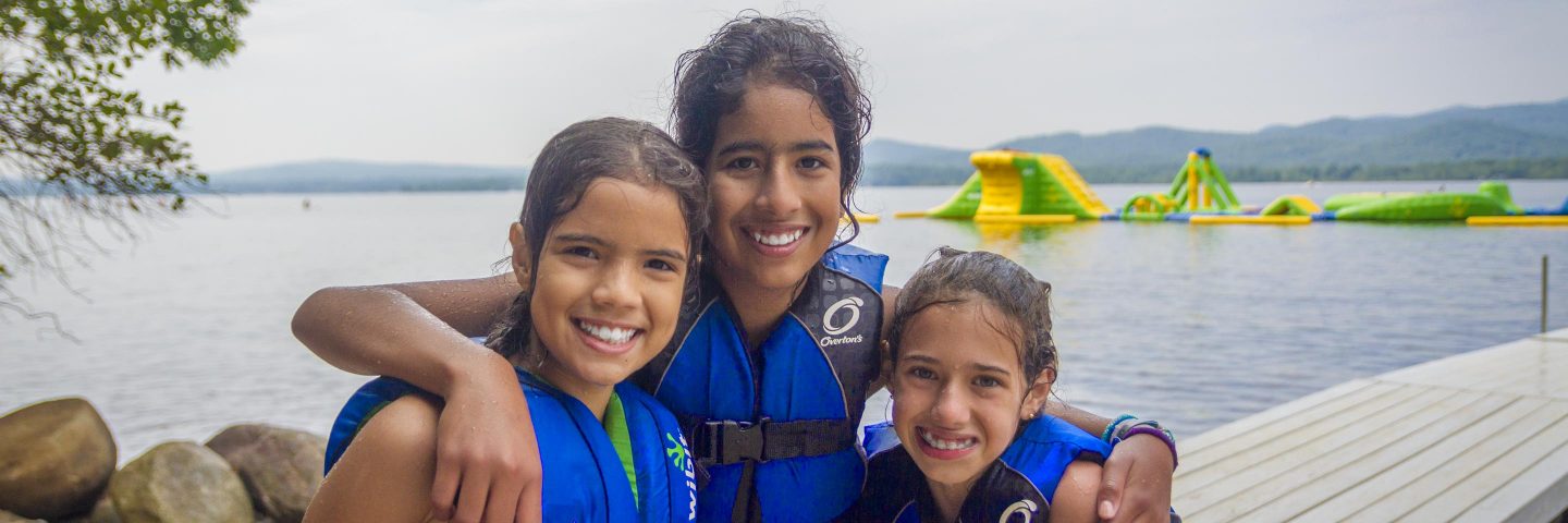 girls at summer camp posing in front of lake