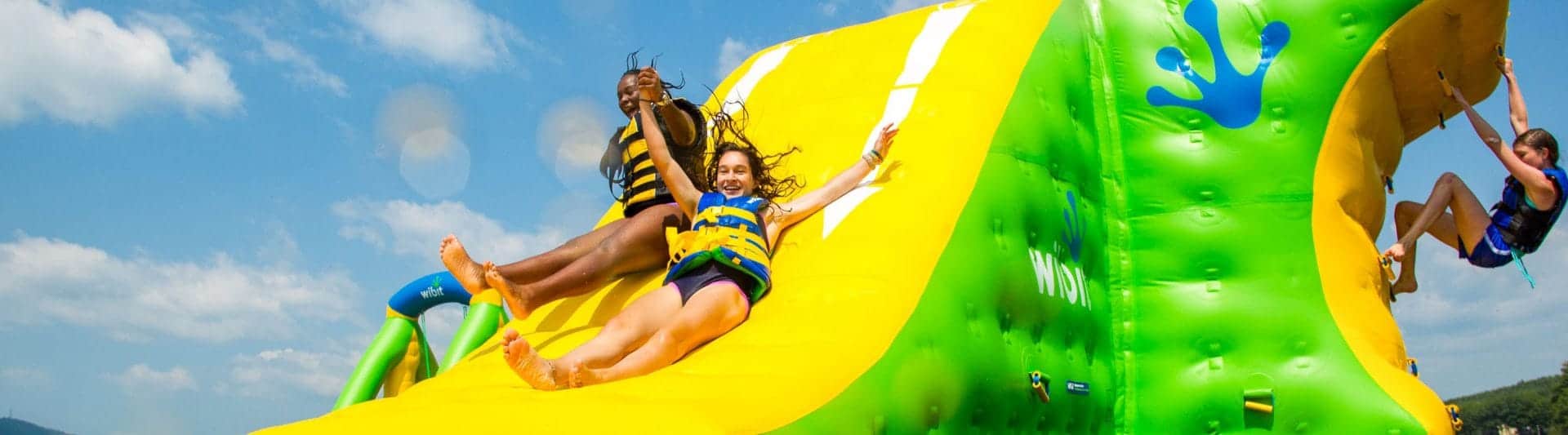 girls sliding down a wibit while another girl climbs the side