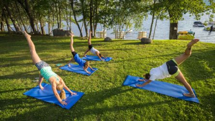 yoga on blue mats on the grass near the lake
