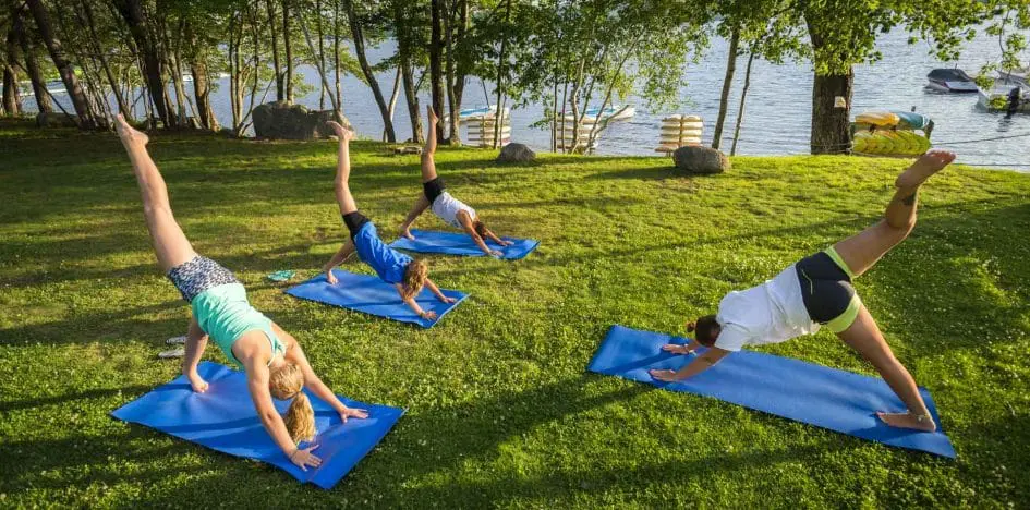 yoga on blue mats on the grass near the lake