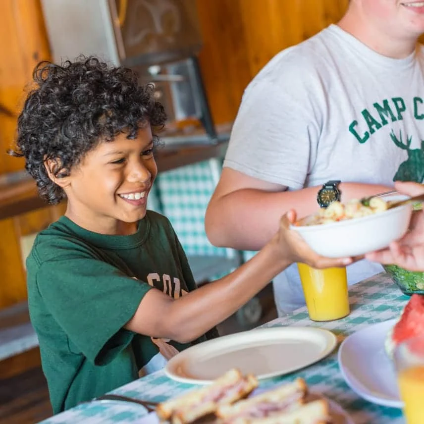 young boy taking a bowl of macaroni pasta