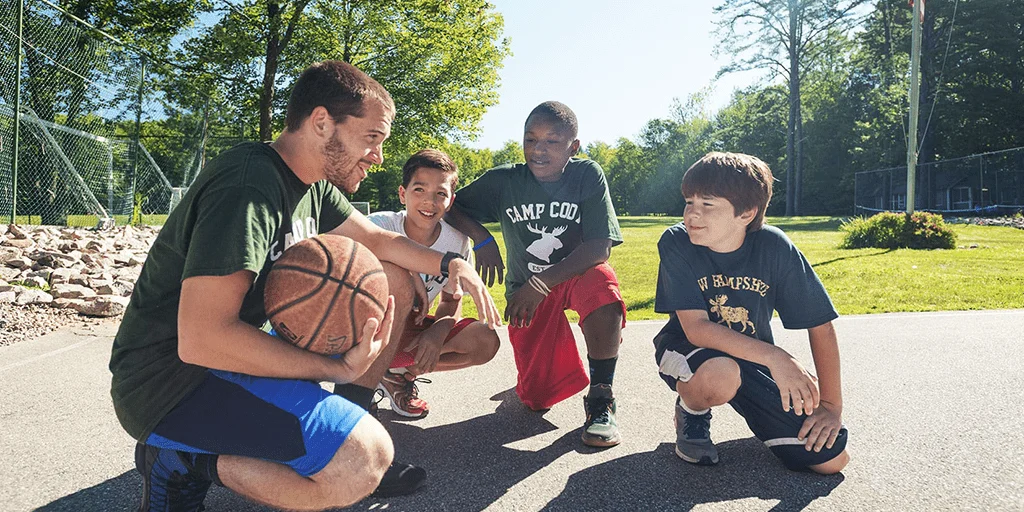 boys and a coach kneeling on a basketball court