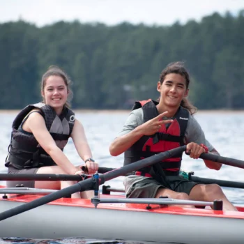 two teens rowing on a lake.