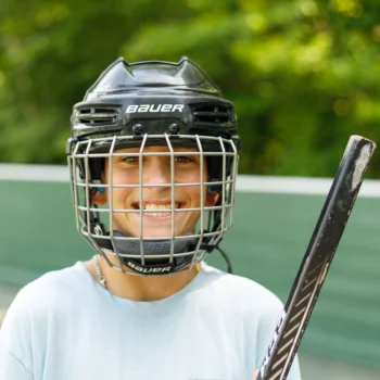 kid in hockey helmet on street hockey court.