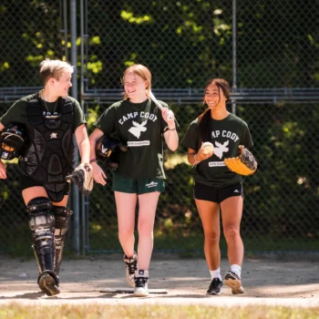 teen girls walking on a softball field.
