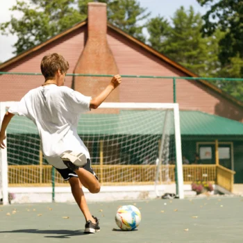 boy shooting on goal on street soccer court.