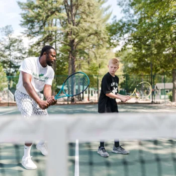 tennis coach teaching boy.