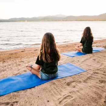 girls practicing yoga on a beach.
